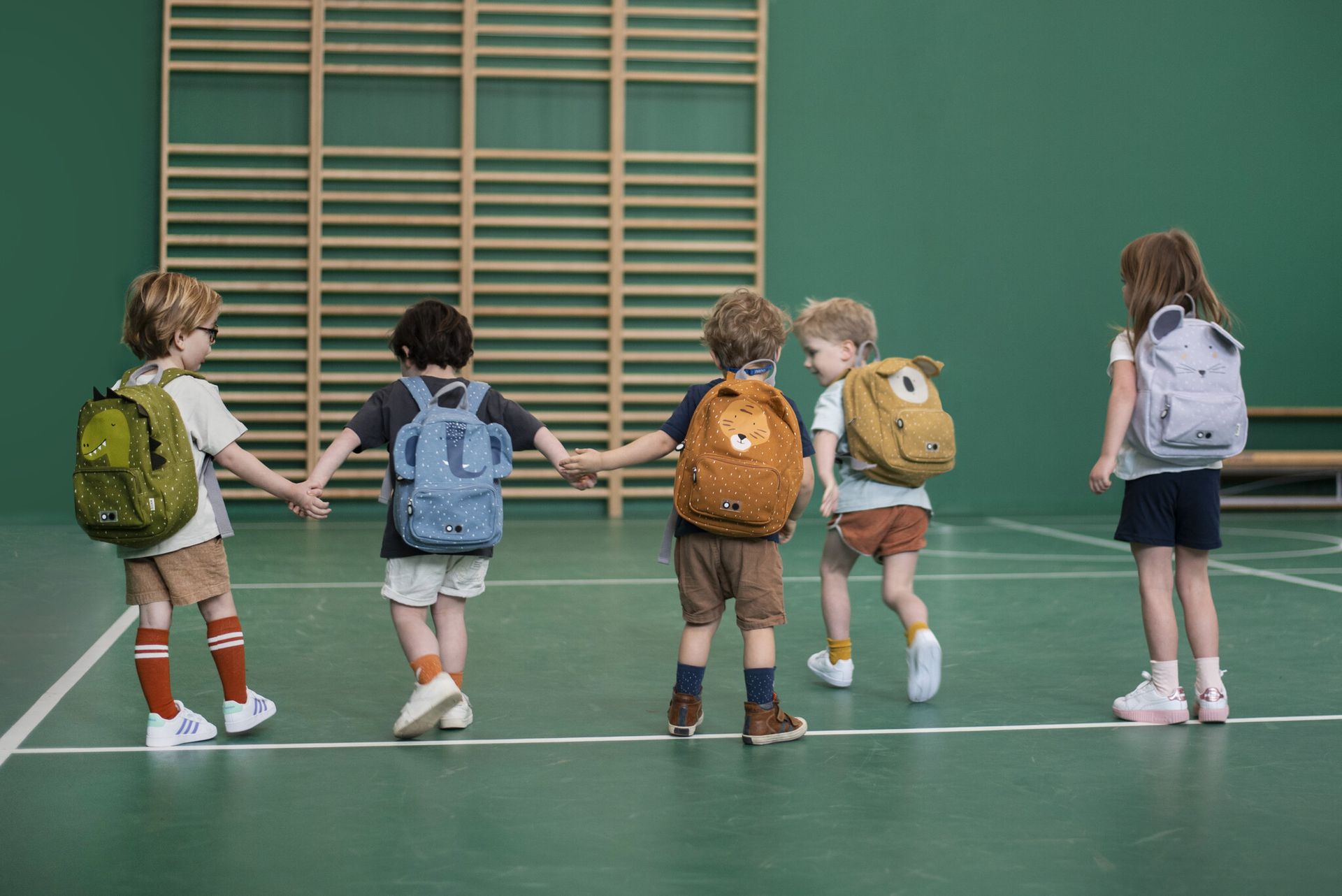 vijf kinderen in de turnzaal, lopend. Elk met een andere Trixie rugzak op de rug vijf kinderen in de turnzaal, lopend. Elk met een andere Trixie rugzak op de rug